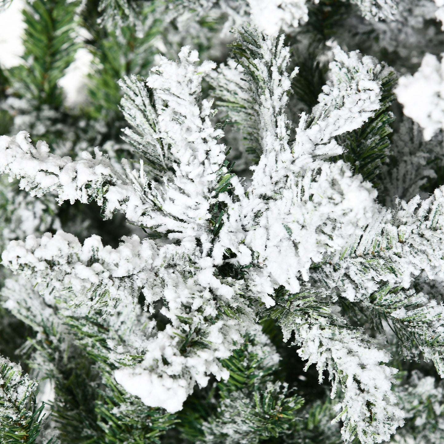 Close-up of unlit flocked Christmas tree for sale showing snowy white artificial snow on green pine needles