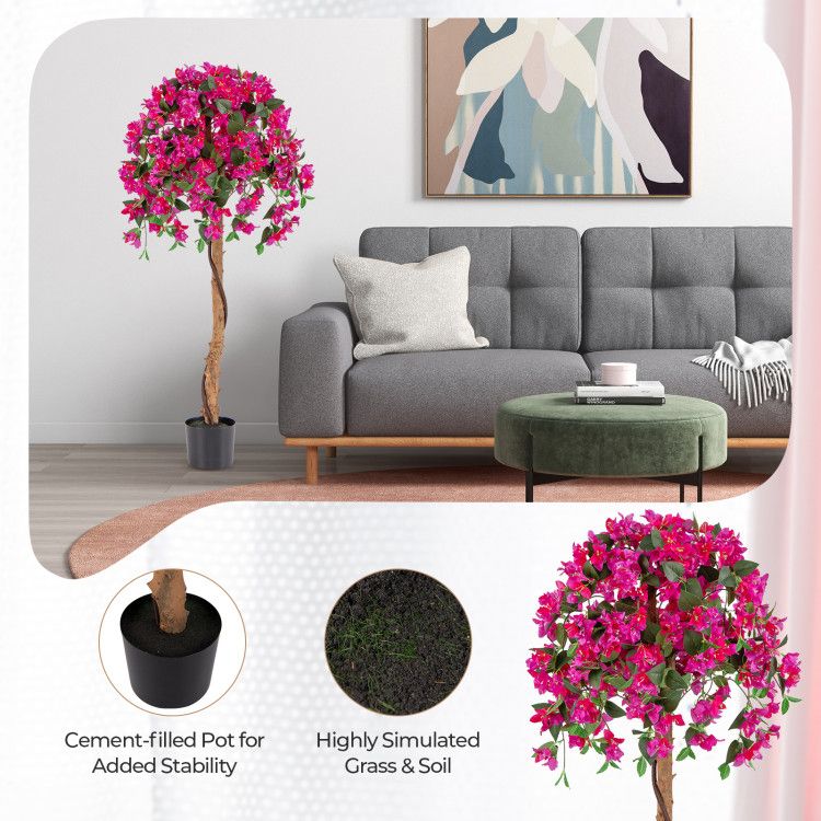 Artificial azalea tree set with vibrant pink flowers in a cement-filled pot next to a gray sofa in living room