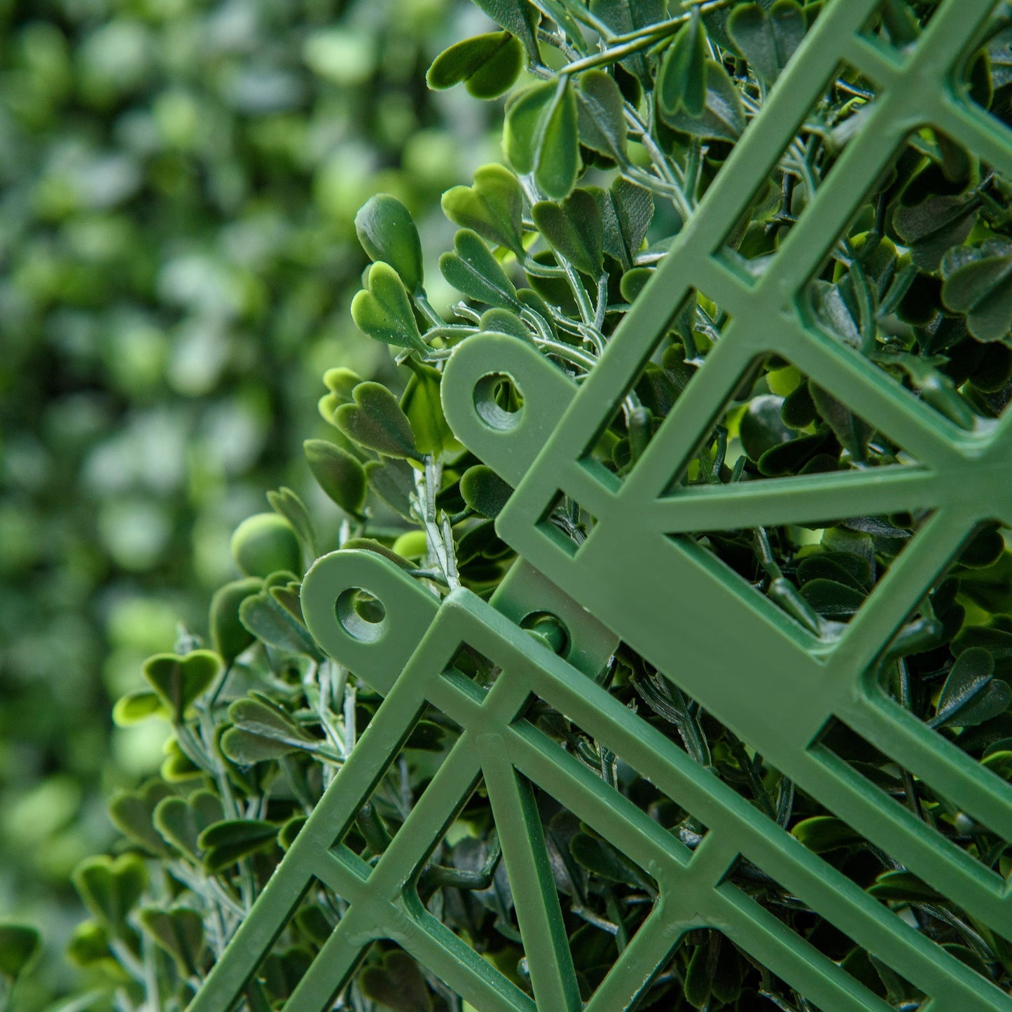 Close-up of green artificial boxwood hedge panels showcasing interlocking design and realistic leaves