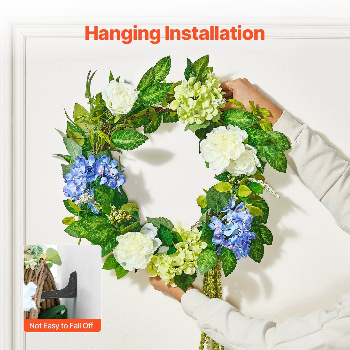 Hands hanging artificial hydrangea wreath with white and blue flowers on white door