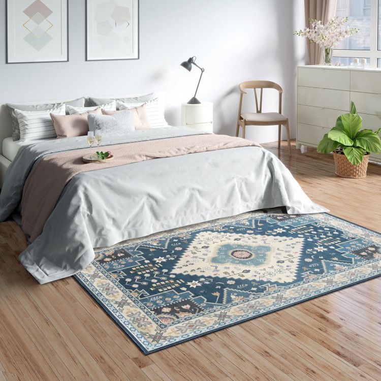 Blue and beige geometric faux wool area rugs in a modern bedroom with wooden flooring and neutral bedding