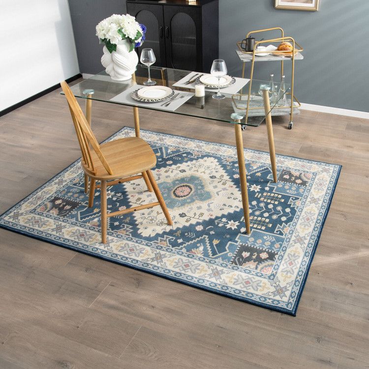 Blue and beige patterned faux wool area rugs under glass dining table with wooden chair