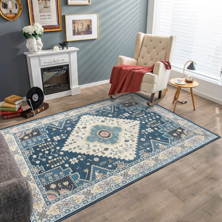 Blue and cream patterned faux wool area rugs in cozy living room with armchair and fireplace