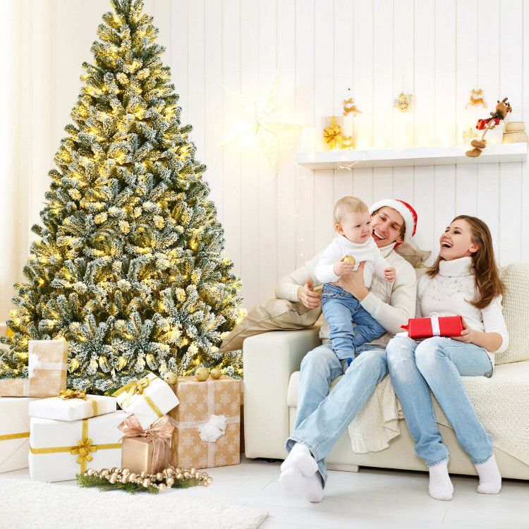 Family enjoying holiday time near pre-lit snow flocked Christmas tree with wrapped presents