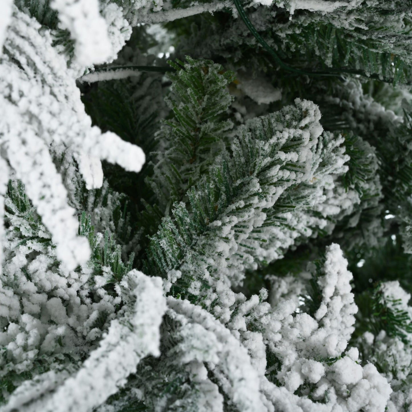 Close-up of green branches covered with white artificial snow on pre-lit snow flocked Christmas tree set
