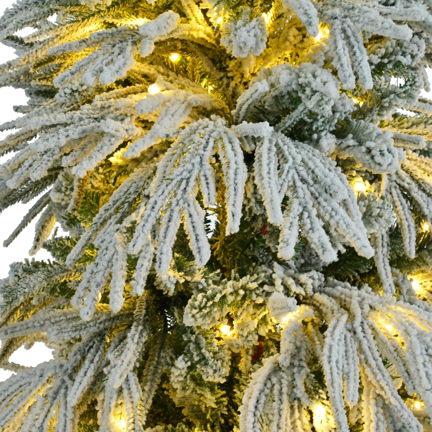 Close-up of pre-lit snow flocked Christmas tree set with warm white lights on frosted branches