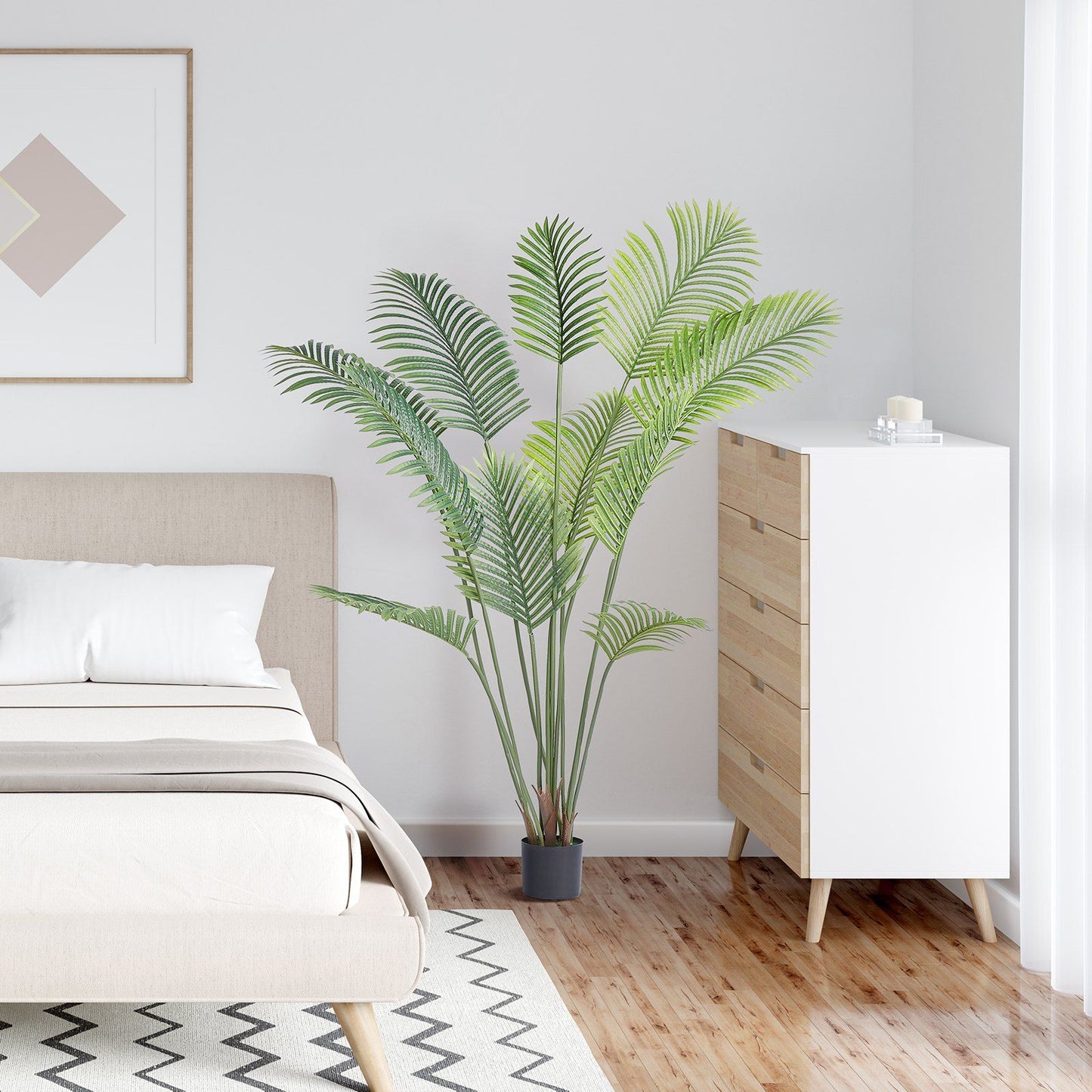 6ft artificial palm tree in a black pot next to bed and wooden dresser in modern bedroom