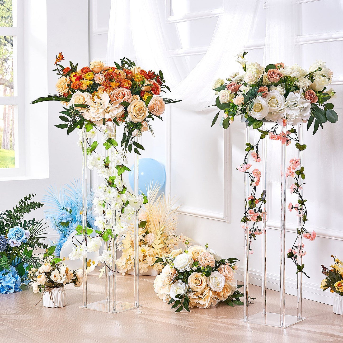 Elegant acrylic wedding flower stands holding lush floral arrangements with roses and greenery