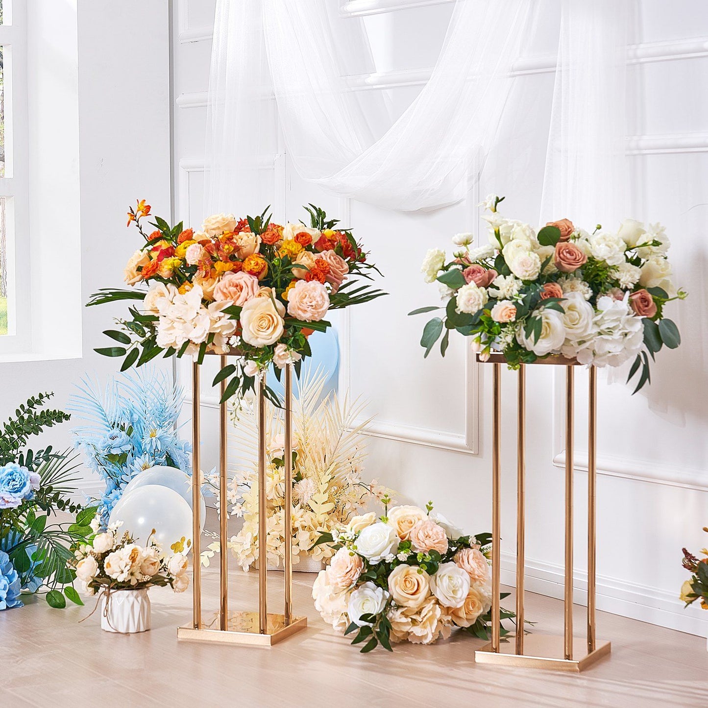 Elegant gold metal wedding flower stands holding colorful and white floral arrangements in a bright room