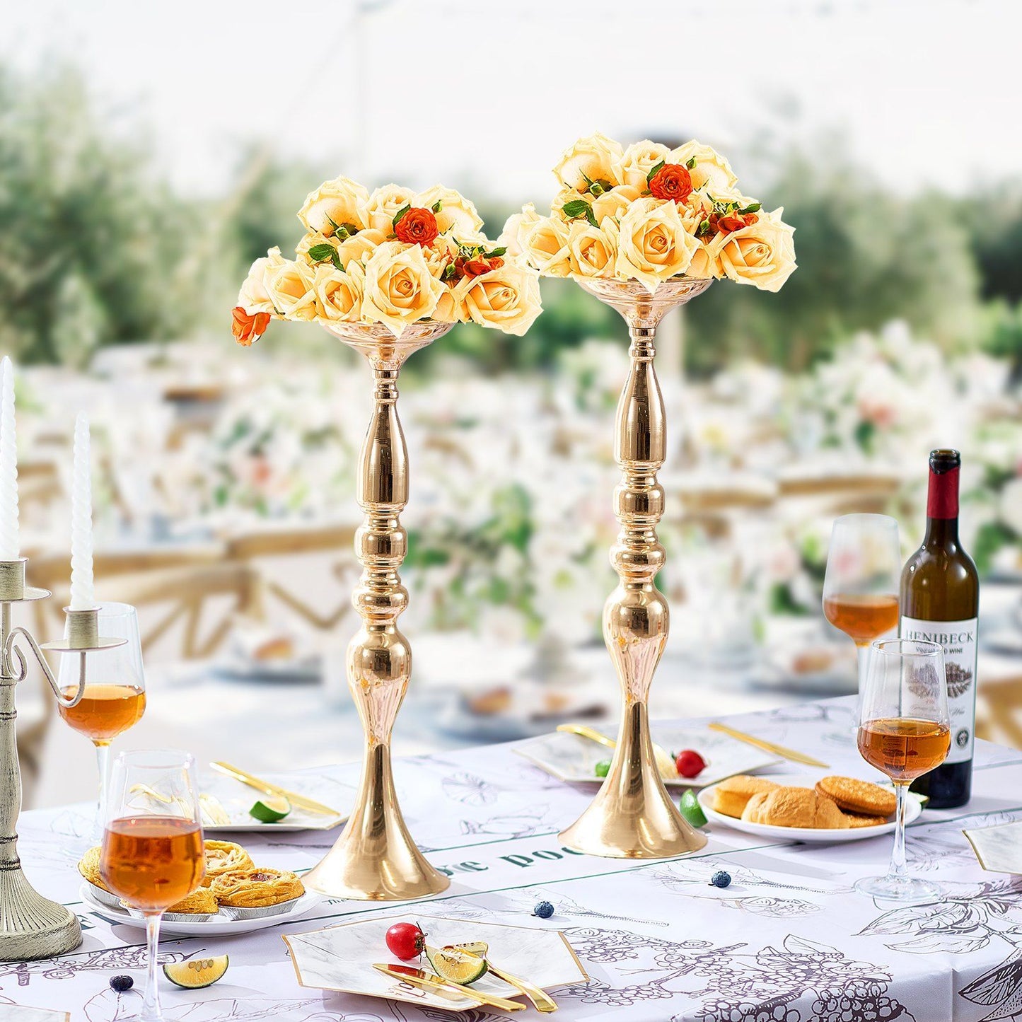 Elegant gold wedding flower stands holding cream and orange rose bouquets on a decorated table