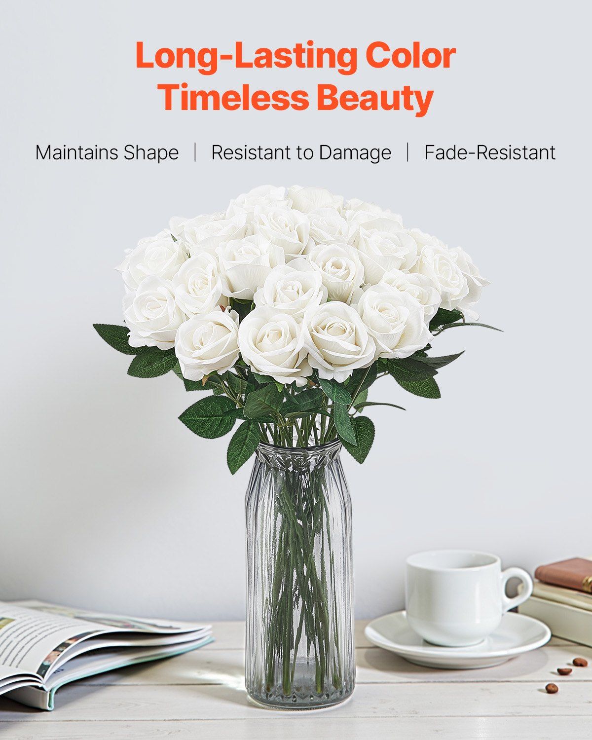 White artificial roses bouquet in clear glass vase on table with coffee cup and book