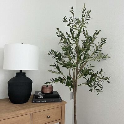 Decorative 6ft artificial olive tree placed beside a stylish lamp and books on a wooden table