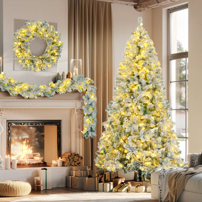 6ft snow flocked Christmas tree set with warm white lights, matching wreath and garland by FauxMart.com in cozy living room