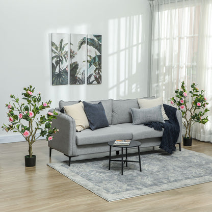 Artificial camellia flowers in pots placed on either side of a modern gray sofa in a bright living room