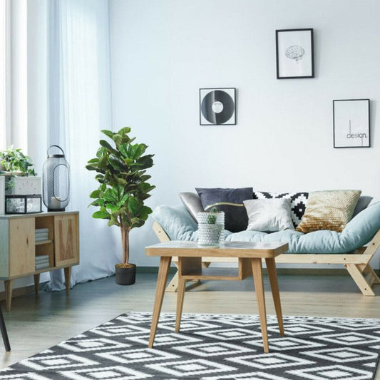 Modern living room with artificial fiddle leaf fig tree in a decorative pot beside a cozy sofa
