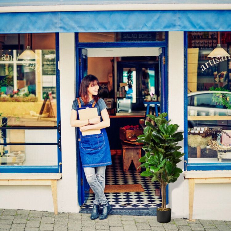 Woman standing outside a cafe with an artificial fiddle leaf fig tree in a black pot