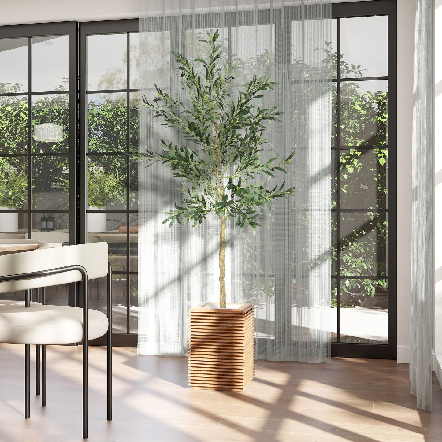 Artificial olive tree indoor in wooden slat planter next to dining table with white chairs