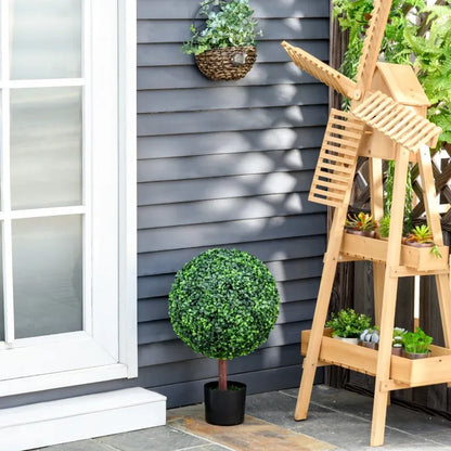 23.5 inch artificial topiary tree in a black pot placed on a patio alongside a wooden plant stand