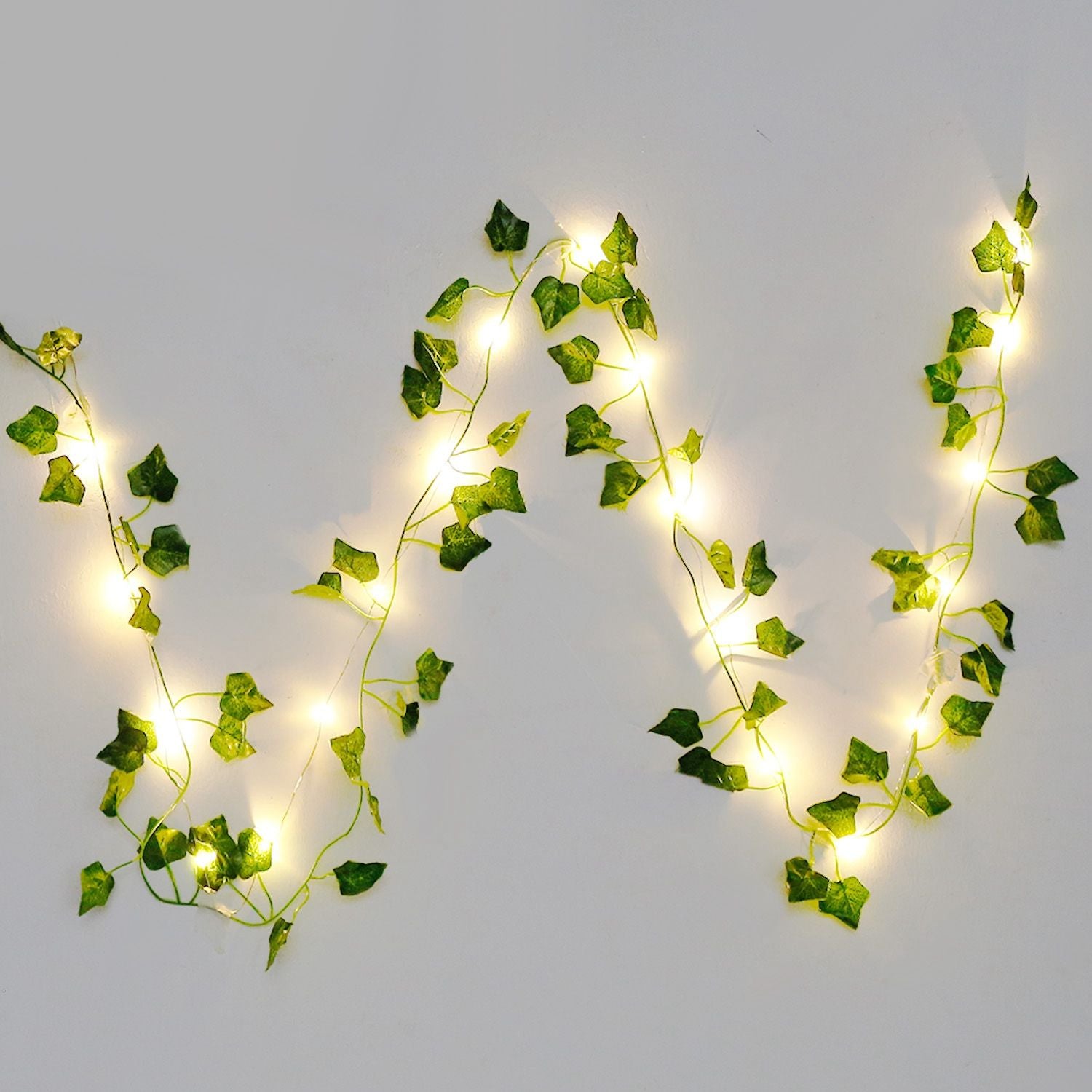 Warm glowing artificial ivy string lights with green leaves on a white background by FauxMart.com