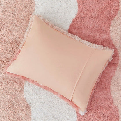 Peach pillow with fringe detail on a wavy ombre faux fur comforter set in pink and white