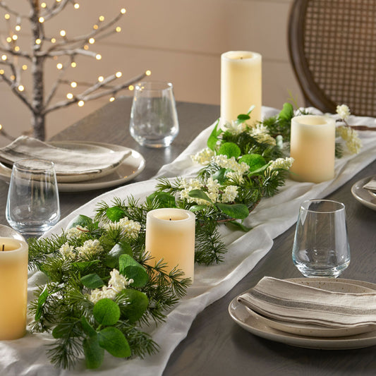 Eucalyptus Christmas garland centerpiece with candles and white flowers on a dining table setting
