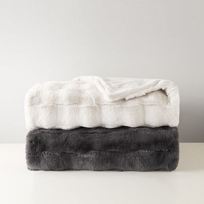 Soft white and dark gray faux fur throw blanket folded and stacked on a white surface
