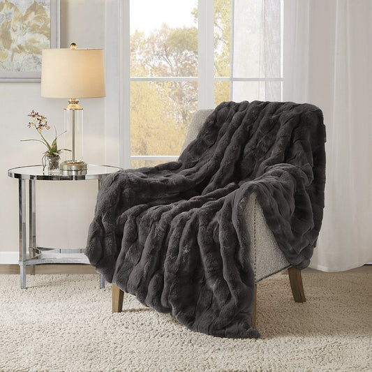 Dark gray faux fur throw blanket draped over a chair in cozy living room setting