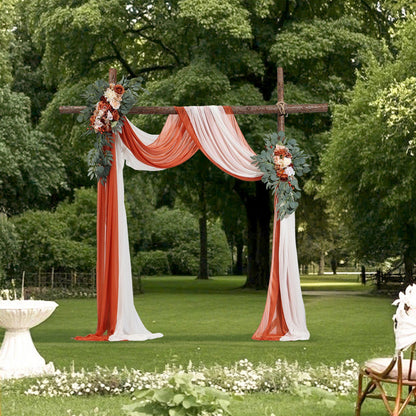 Outdoor wedding arch decorated with burnt orange wedding arch flowers and white draped fabric in a garden