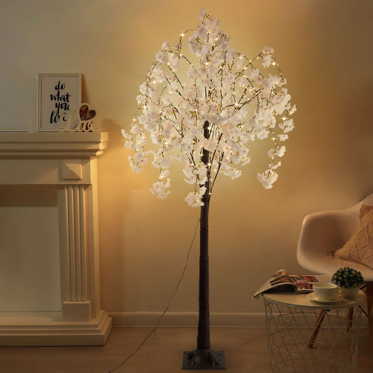 Lighted cherry blossom tree decor with white flowers and warm LED lights in a cozy living room setting