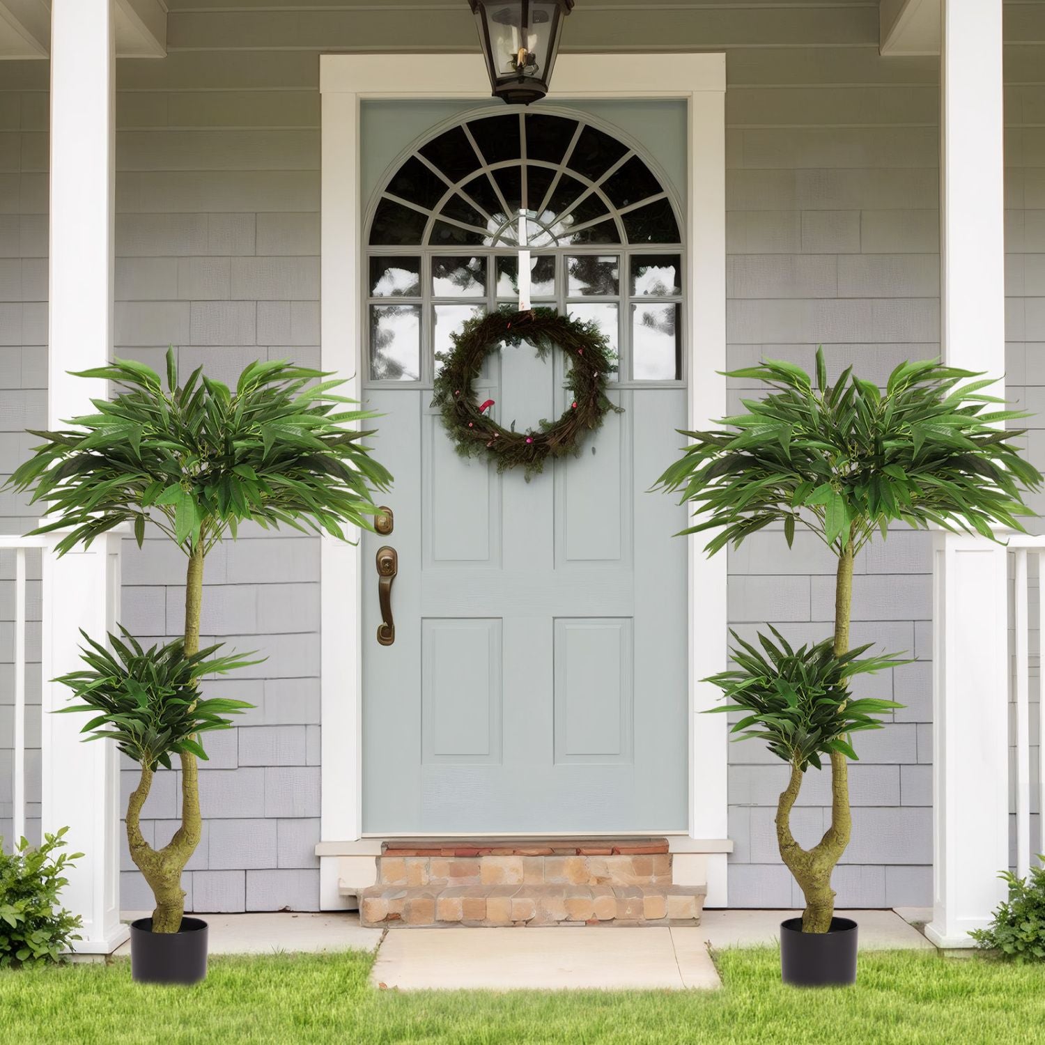 Two long artificial plants for indoors placed by a welcoming entrance with a decorative wreath