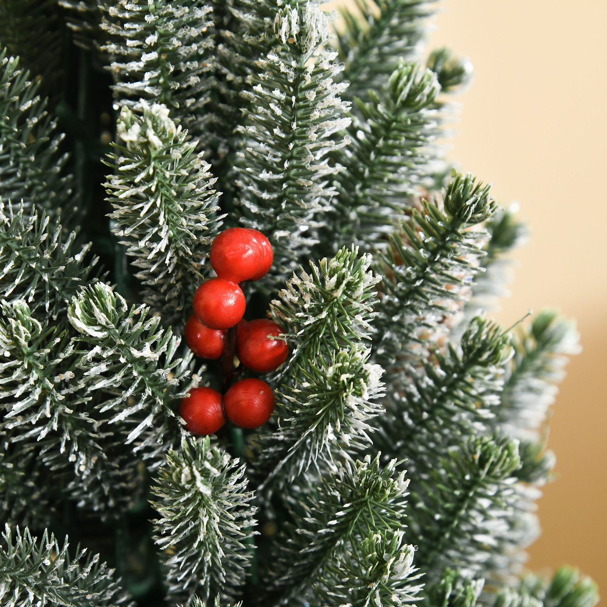 Miniature snow flocked Christmas tree with red berries for festive holiday decoration