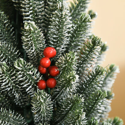 Miniature snow flocked Christmas tree with red berries for festive holiday decoration