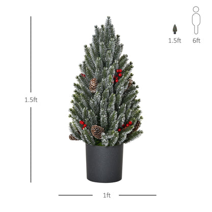 Miniature snow flocked Christmas tree decorated with pinecones and red berries in a black pot