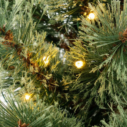 Close-up of pre-lit artificial Christmas tree with warm white lights for festive decoration