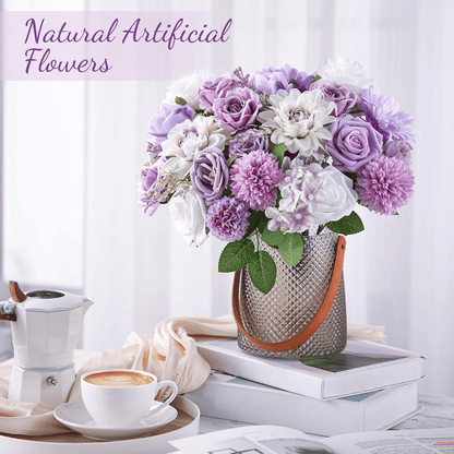 Purple artificial flower arrangement in textured vase with green leaves on a stack of books beside a coffee cup and white coffee maker