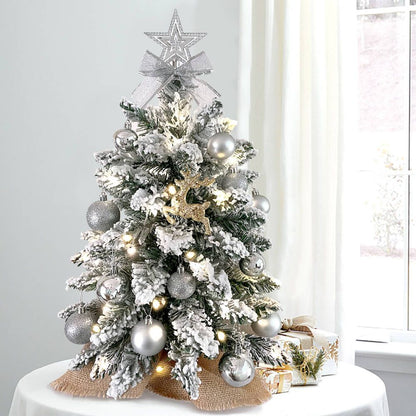 Small Xmas tree for office desk with snow-flocked branches, silver ornaments, lights, and star topper