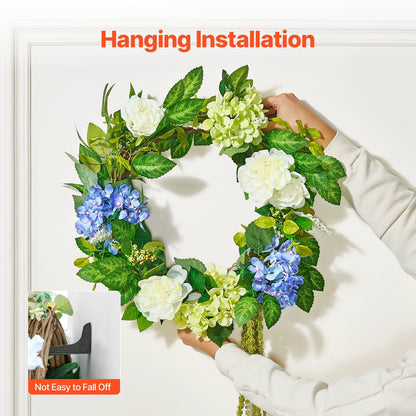 Hands hanging artificial hydrangea wreath with white and blue flowers on white door