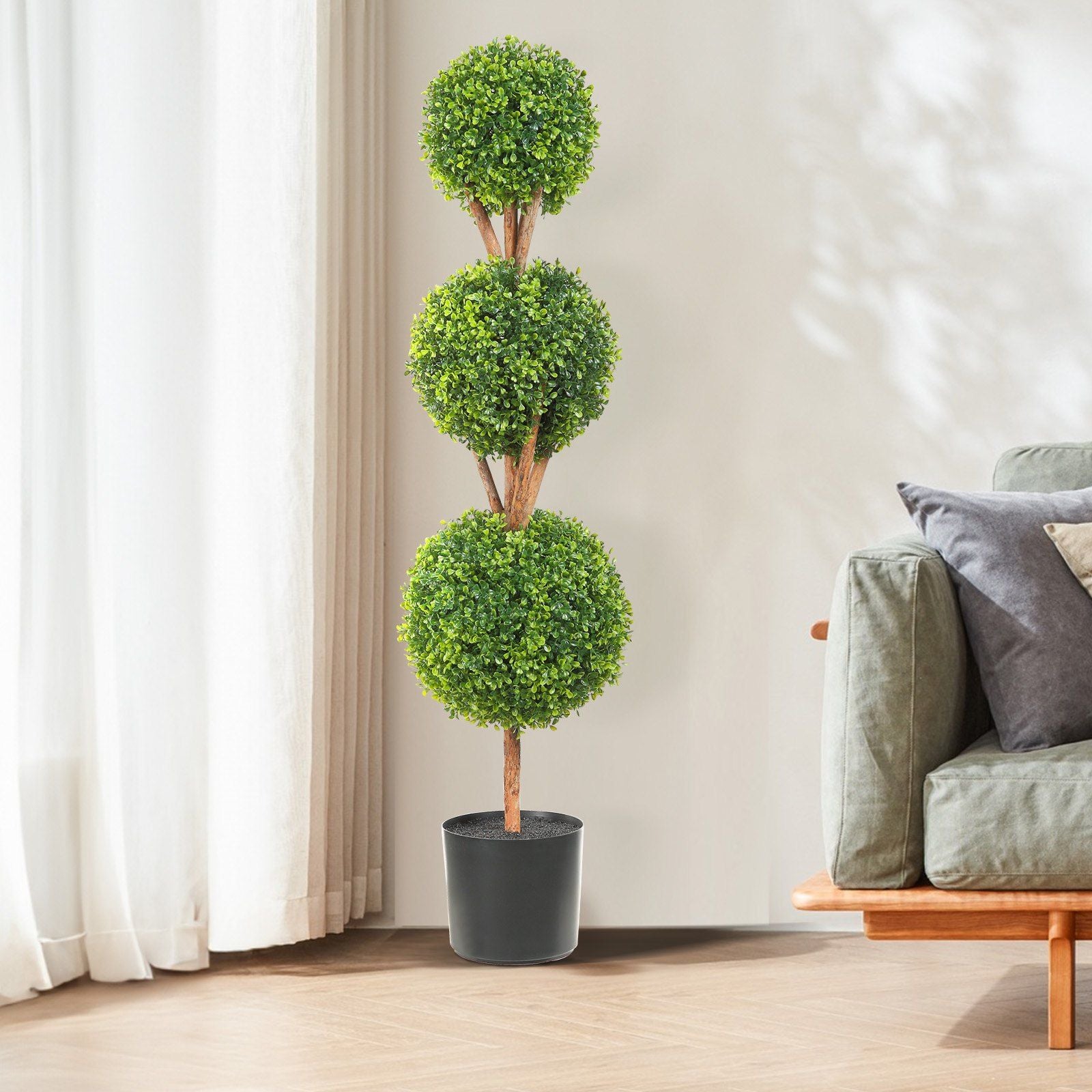 Faux boxwood trees set with three green ball-shaped topiaries in black pot by sofa