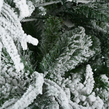 Close-up of green branches covered with white artificial snow on pre-lit snow flocked Christmas tree set