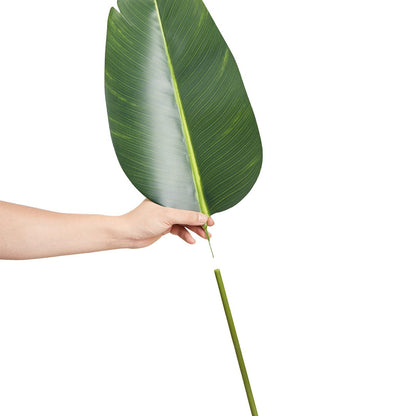 Hand holding large green leaf and separate stem of artificial birds of paradise tree from FauxMart.com