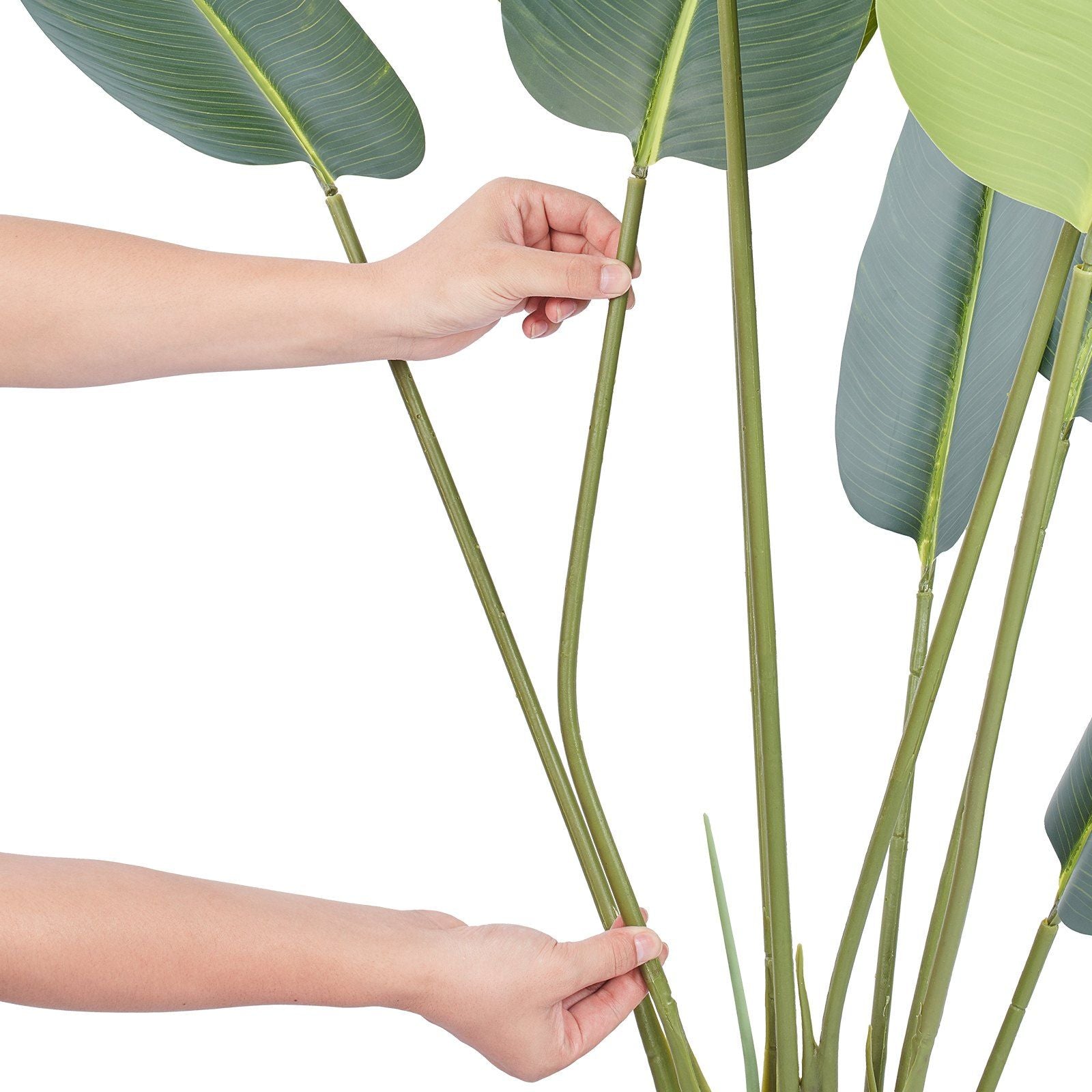 Hands adjusting green leaves on an artificial birds of paradise tree by FauxMart.com