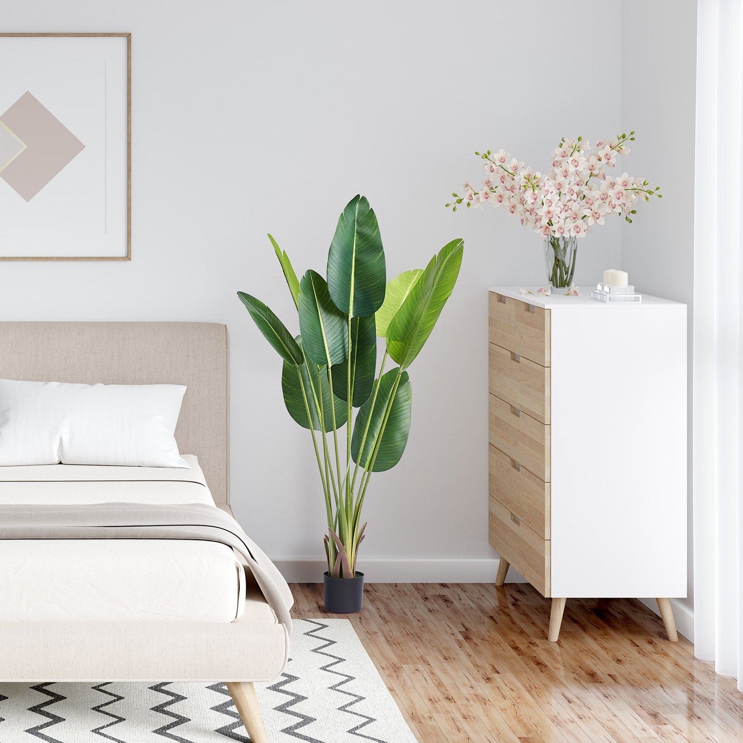 Modern bedroom with artificial birds of paradise tree in black pot next to wooden dresser and bed