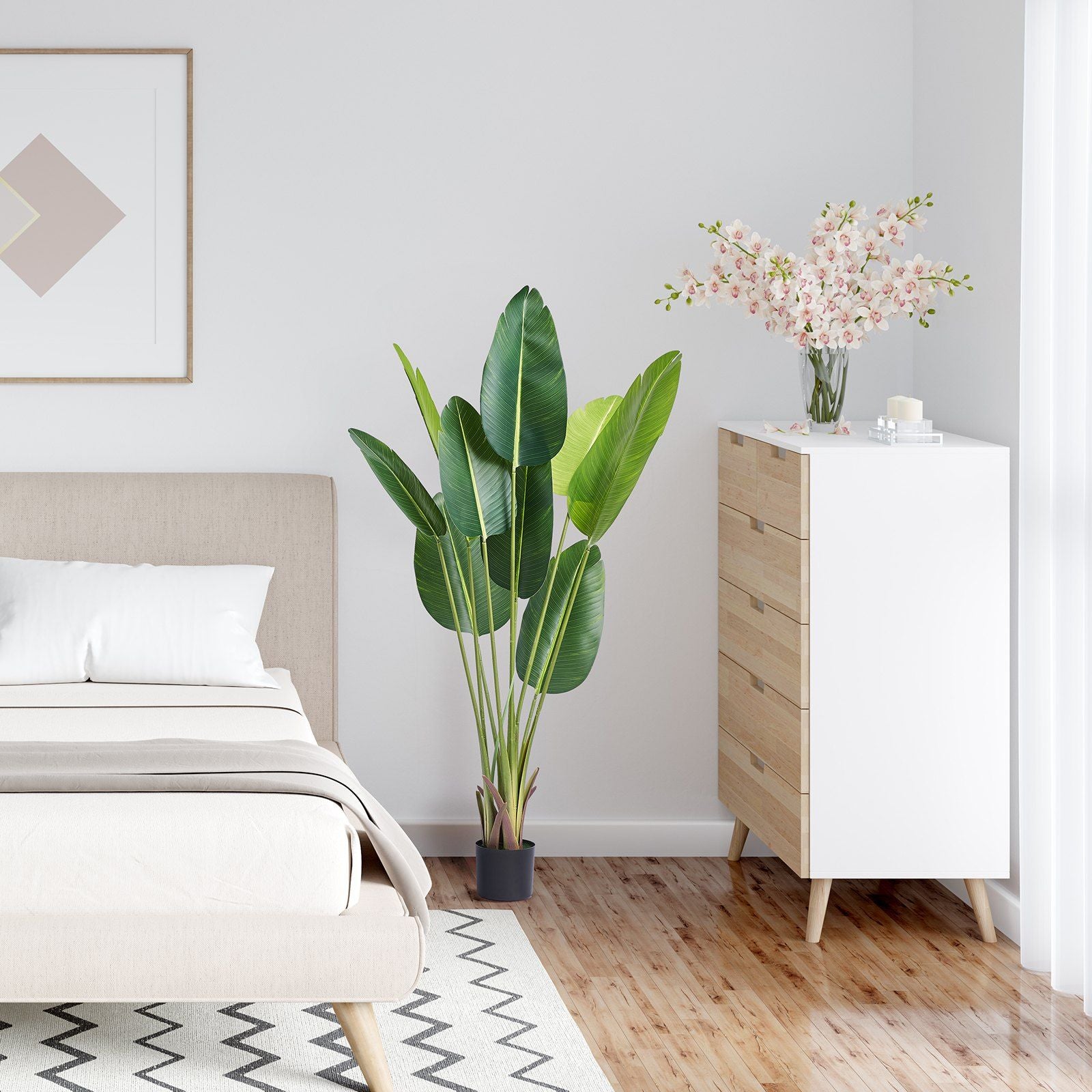 Modern bedroom with artificial birds of paradise tree in black pot next to wooden dresser and bed