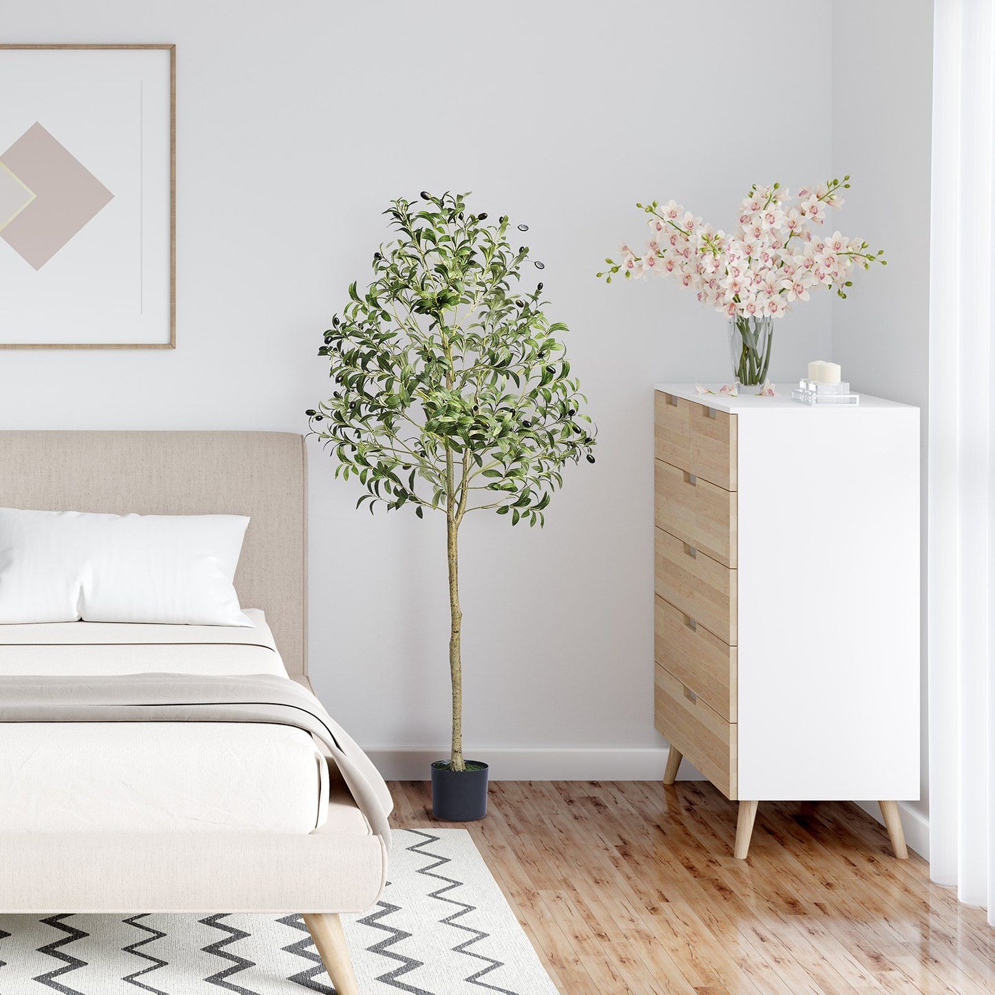 Artificial olive tree 5ft in black pot placed beside beige bed and white dresser in modern bedroom