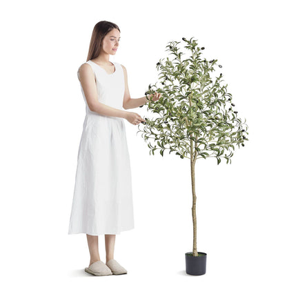 Woman in white dress standing next to artificial olive tree 5ft in black pot from FauxMart.com