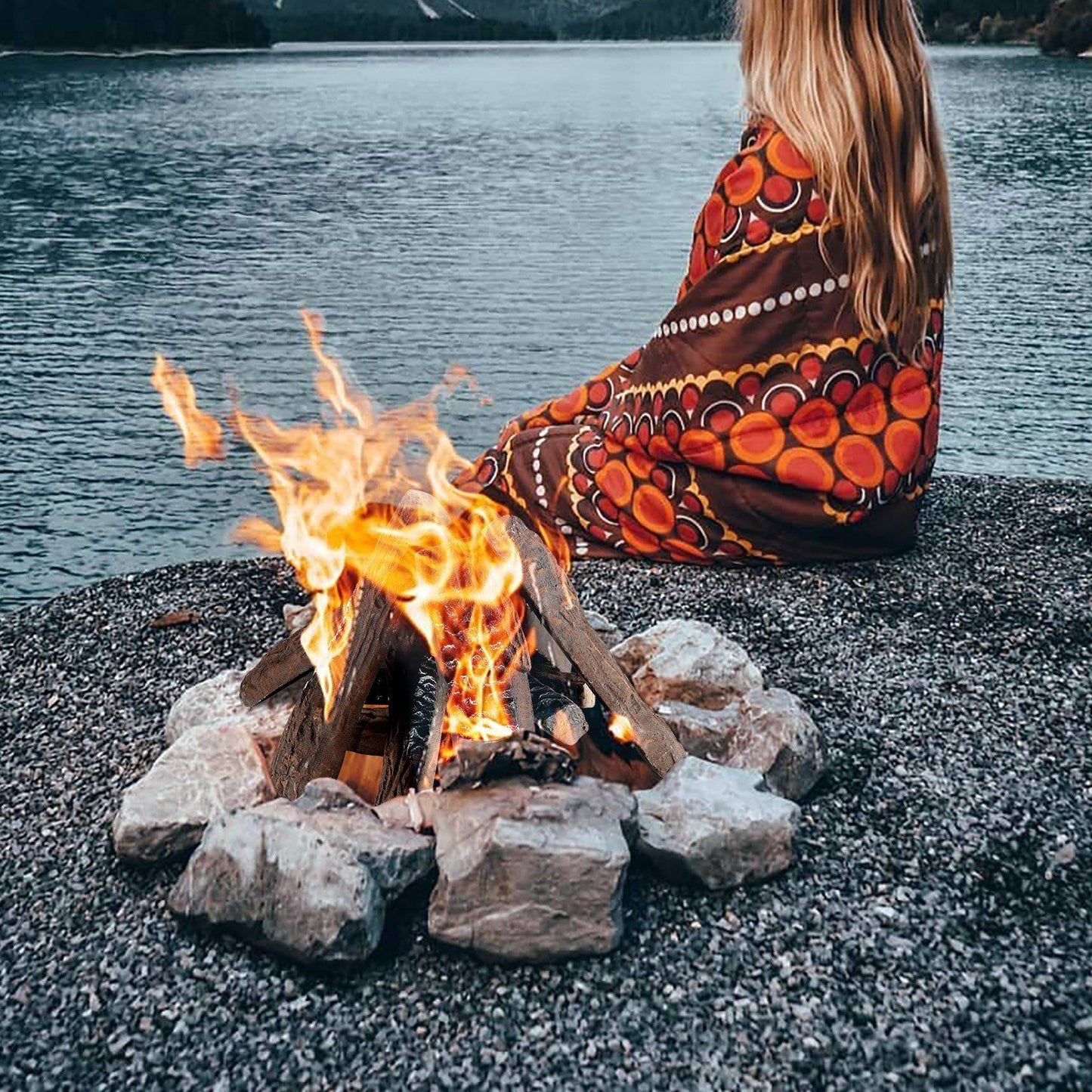 Realistic gas fireplace logs arranged in a campfire setting with flames near a lake shore