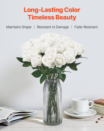 White artificial roses bouquet in clear glass vase on table with coffee cup and book